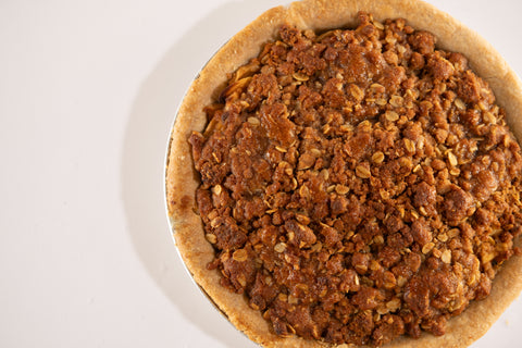 Close-up, overhead view of a vegan and gluten-free apple crumb pie with a golden brown oat topping in a rustic crust.