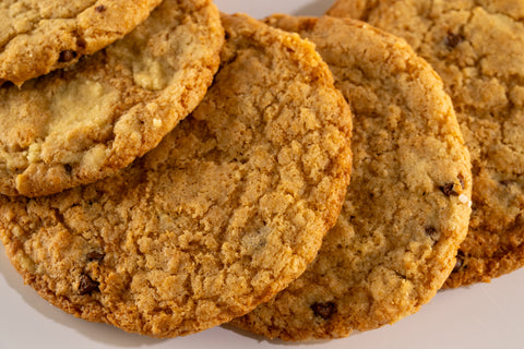 A close-up of chocolate chip cookies, displayed on a white background. The cookies are slightly chewy with visible chocolate chips.