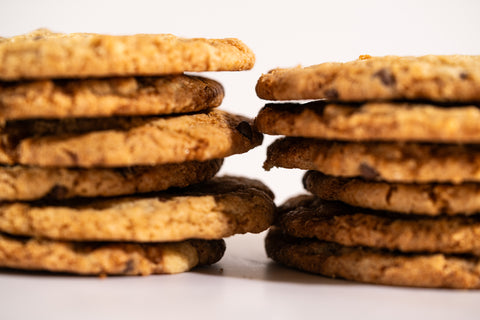 A side view of set of twelve golden-brown chocolate chip cookies, displayed on a white background. The cookies are slightly chewy with visible chocolate chips.