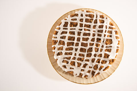 A top view of a round cinnamon crumb cake topped with a lattice-like white icing drizzle.