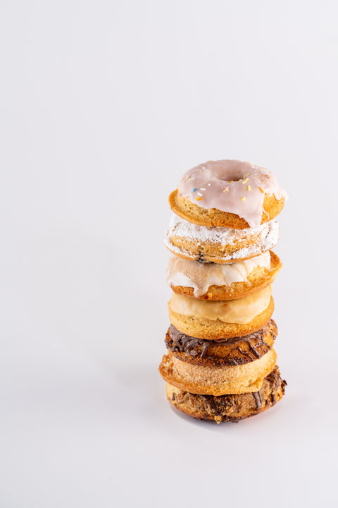 A minimalist image featuring a tall, neatly stacked tower of assorted donuts, each with unique toppings.