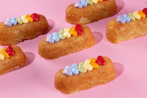 Six golden brown twinkies topped with rainbow frosting