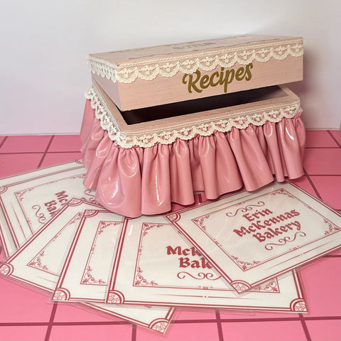 Blush recipe box with lace details on a pink tile floor 