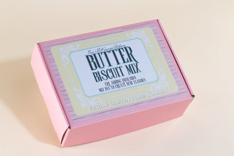 Closed pink packaging box of Erin McKenna's Bakery Butter Biscuit Mix with decorative label stating vegan, gluten-free, and kosher on beige background