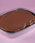 Chocolate cake in a metal pan on a pink background