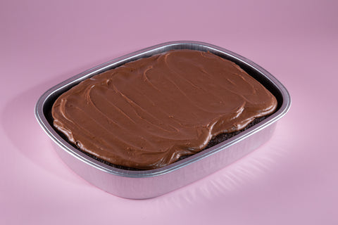 Chocolate cake in a metal pan on a pink background
