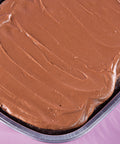 Chocolate frosted cake in a pan on a pink background