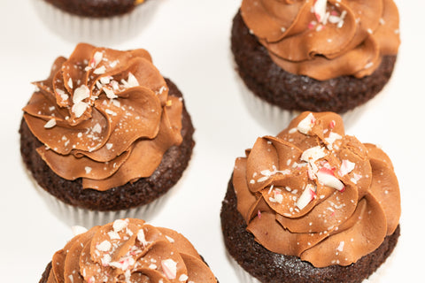 Close-up of brownie cupcakes featuring rich chocolate peppermint frosting and festive pink and white candy cane sprinkles