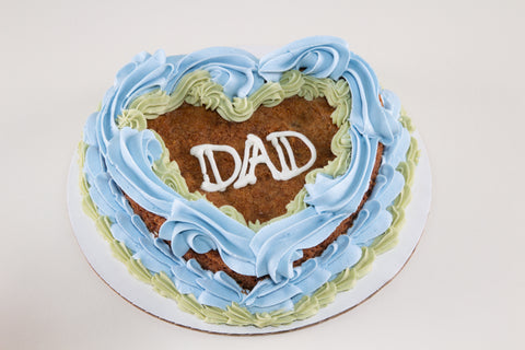 Heart-shaped cake with 'DAD' written on it, decorated with blue and green icing.