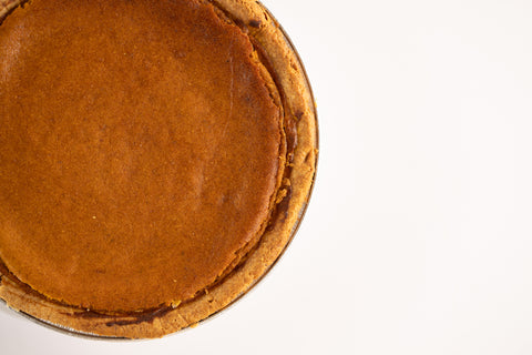 Vegan, gluten-free pumpkin pie displayed on a white surface.