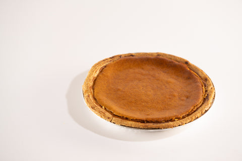 Side view of a whole pumpkin pie showing the thick, golden-brown crust.