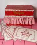 Red recipe box with lace details on a pink tile floor 