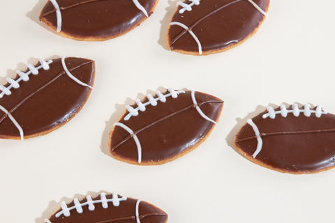 Football-shaped vegan sugar cookies with chocolate icing and white laces decoration