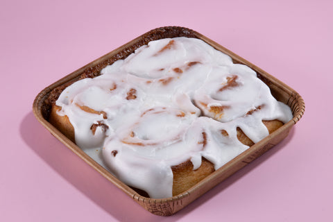 Vegan gluten-free cinnamon rolls with vanilla glaze in woven basket, kosher certified breakfast treats.