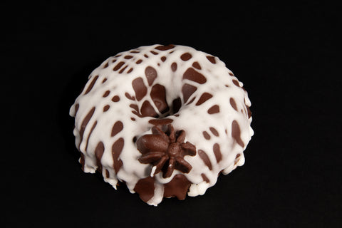 Close-up of allergy-friendly chocolate Halloween donut decorated with white frosting cobweb pattern and chocolate spider - gluten-free spider web donut