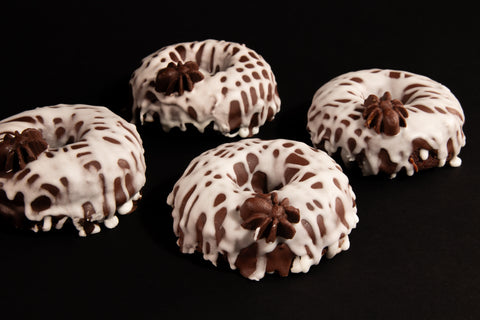 Group of four gluten-free Halloween spider donuts with dripping white glaze and chocolate spiders - dairy-free spooky donuts side angle
