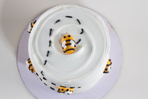 Top view of gluten-free honey apple cake with bee fondant decorations and black sprinkle details, kosher certified