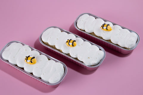 Close-up of honey apple mini cake flight showing individual rose gold tins with bee-decorated mini cakes for Rosh Hashanah