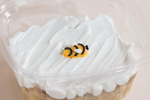Individual honey apple cake slice in clear container with white frosting and bee decoration, vegan and gluten-free for High Holidays