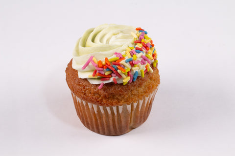 Single vanilla cupcake with light green frosting in a perfect swirl topped with rainbow sprinkles, showcasing Erin McKenna's gluten-free and vegan Saint Patrick's Day treat.