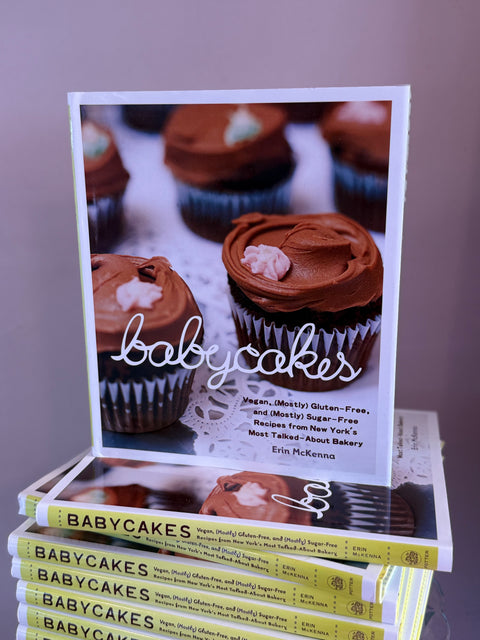 A stack of books with chocolate cupcakes on a pink background