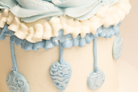 "Detailed view of shimmering blue vintage-style ornaments with intricate piped designs and sugar crystal accents