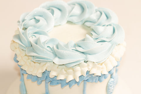 Close-up of layered ruffles in white and powder blue frosting with crystalline rosette details on winter-themed cake