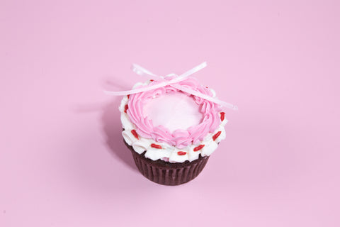 Chocolate and vanilla cupcakes decorated with pink buttercream frosting and white ribbon bows, set against a pastel pink background.