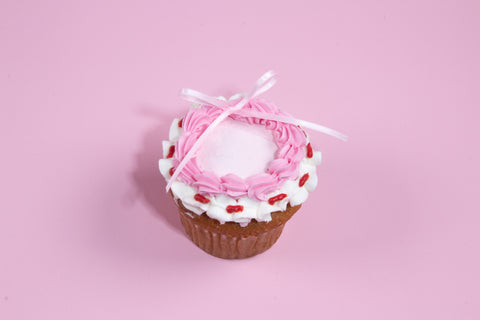 Chocolate and vanilla cupcakes decorated with pink buttercream frosting and white ribbon bows, set against a pastel pink background.