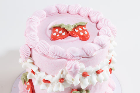 Pink cake with strawberry decorations on a white background