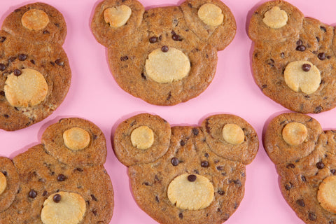 Close up of six bear-shaped cookies with chocolate chips on a pink background
